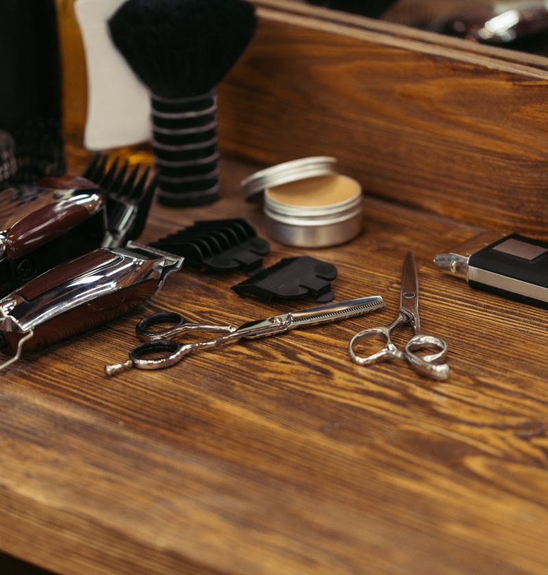 close-up view of various barber tools on wooden shelf in barbershop