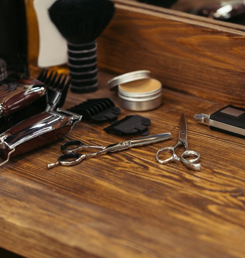 close-up view of various barber tools on wooden shelf in barbershop